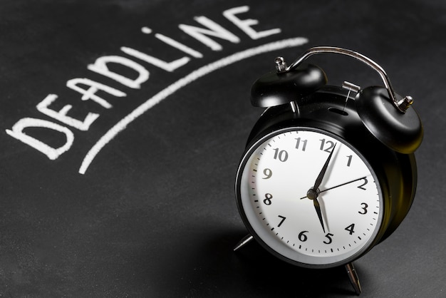 Deadline text written on chalkboard with alarm clock