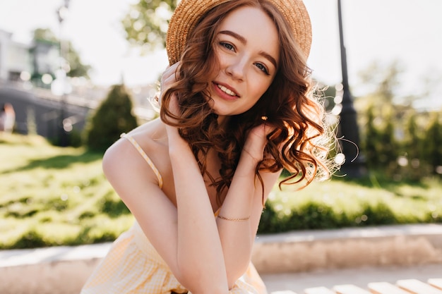 Девушка Debonair кавказская с рыжими волосами позирует в парке. Jocund рыжеволосая молодая женщина проводит летние выходные на открытом воздухе.