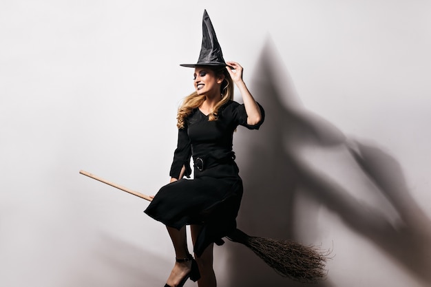 Debonair girl in witch costume enjoying carnival.  photo of dreamy fair-haired lady having fun in halloween.