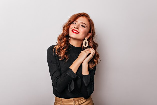 Debonair stylish woman in black blouse smiling.  graceful european girl wears golden earrings.