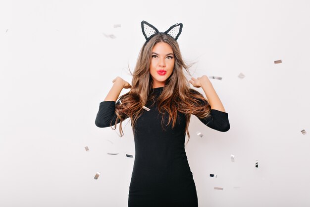 Debonair woman posing under confetti in studio