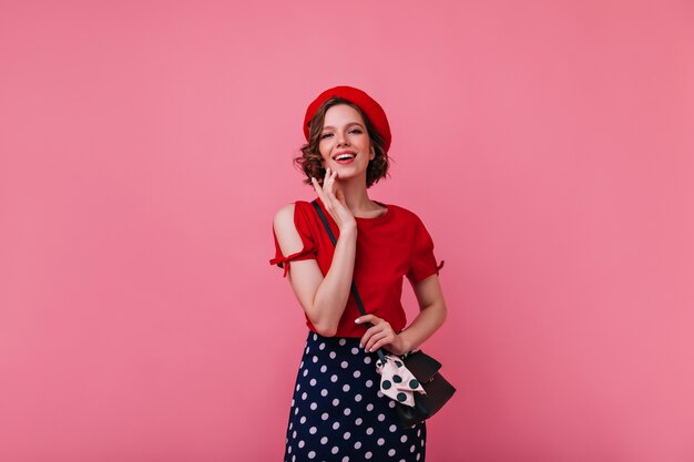 Debonair woman in spring french outfit enjoying photoshoot. Portrait of caucasian girl in beret smiling.