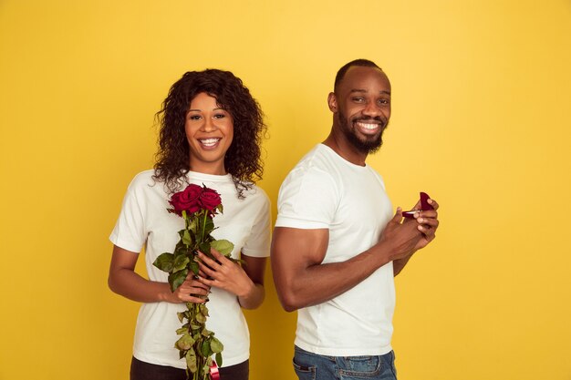 Decision. Valentine's day celebration, happy african-american couple isolated on yellow  wall. Concept of human emotions, facial expression, love, relations, romantic holidays.