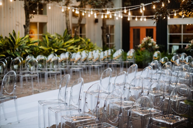 Decorated ceremonial area outdoors with modern transparent chairs and beautiful festoon
