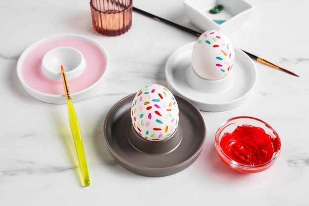 Decorated easter egg on plate with paint and paintbrush