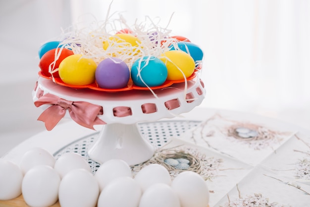 Decorated easter eggs with shredded papers on cakestand over the table