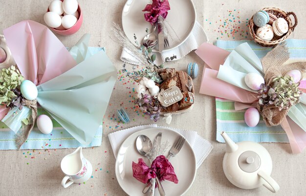 Decorated festive table with Easter dessert, tea and eggs flat lay. Happy Easter concept.