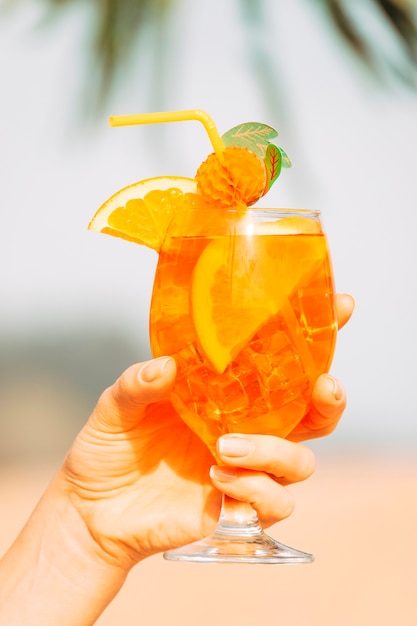 手で冷やしたオレンジ色の飲み物の装飾が施されたガラス