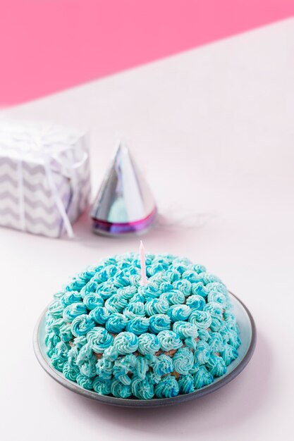 Decorated homemade cake with candle on plate against dual backdrop