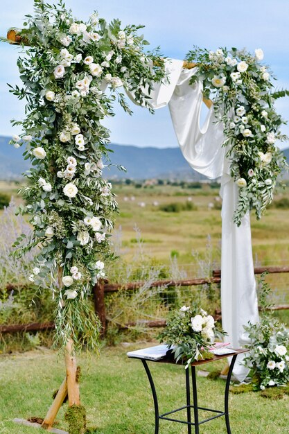屋外の庭にある緑と白のトルコギキョウで飾られた結婚式のアーチ