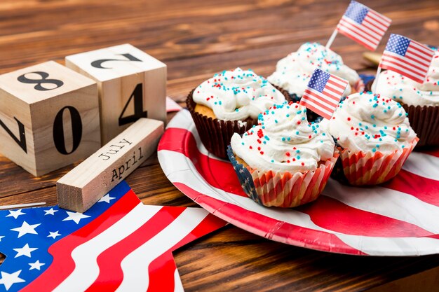 Decorated whipped cream cupcakes with American flags on plate and symbols of independence 