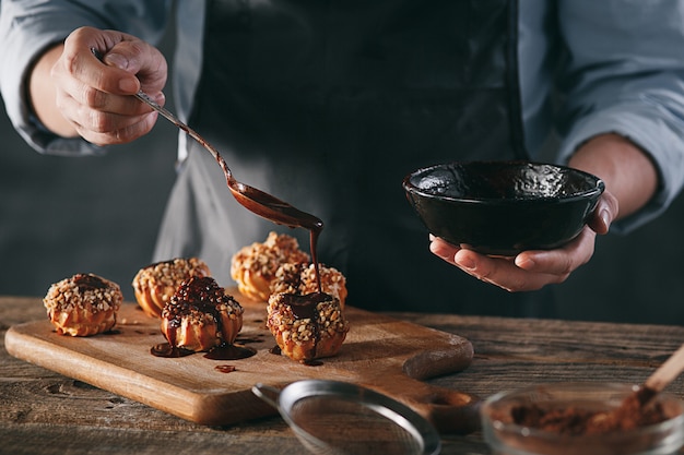 Decorating delicious homemade eclairs with chocolate and peanuts