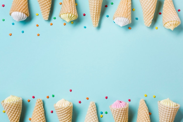 Decoration of waffle cone with aalaw and sprinkles on blue backdrop