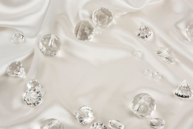 Декоративные прозрачные бриллианты на текстурированном фоне белой ткани