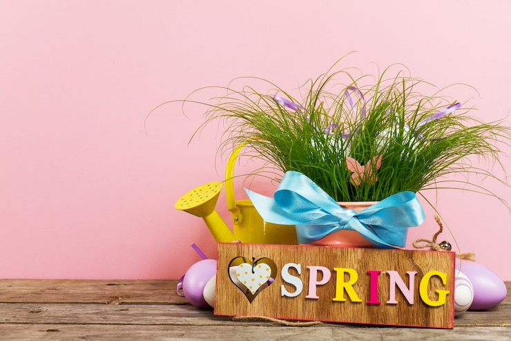 Free Photo decorative colorful eggs in flower pot with fresh green grass on wooden table on pink background. horizontal with copy space.