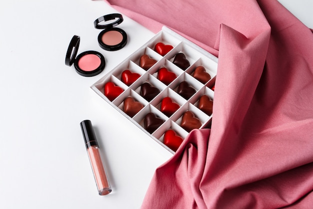 Free photo decorative cosmetics and chocolate over white surface