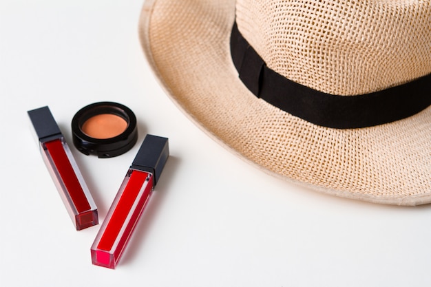 Decorative cosmetics and hat over white surface