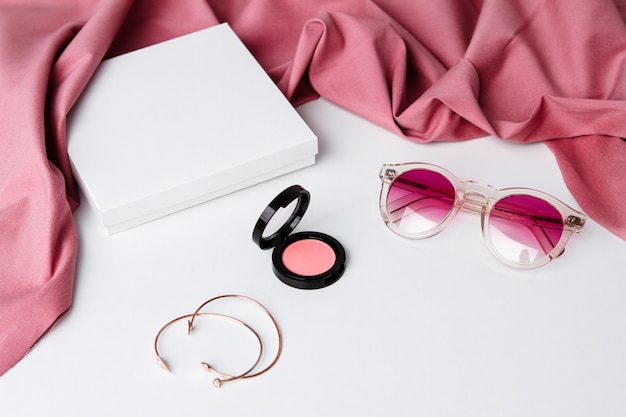 Decorative cosmetics sunglasses and accessories over white surface