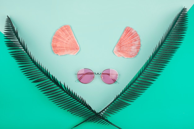 Декоративные скрещенные пальмовые листья; гребешок и солнцезащитные очки на мятном фоне