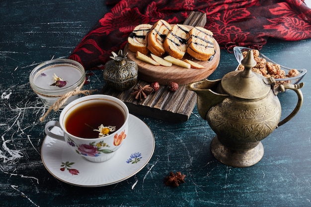 A decorative cup of herbal tea with rollcake slices.