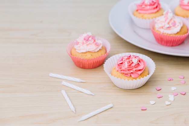 Decorative cupcake with cream and sprinkles on wooden desk