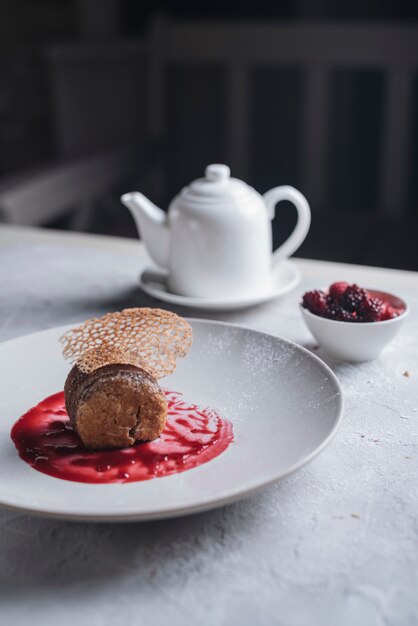 Decorative dessert with red berries sauce on white ceramic plate