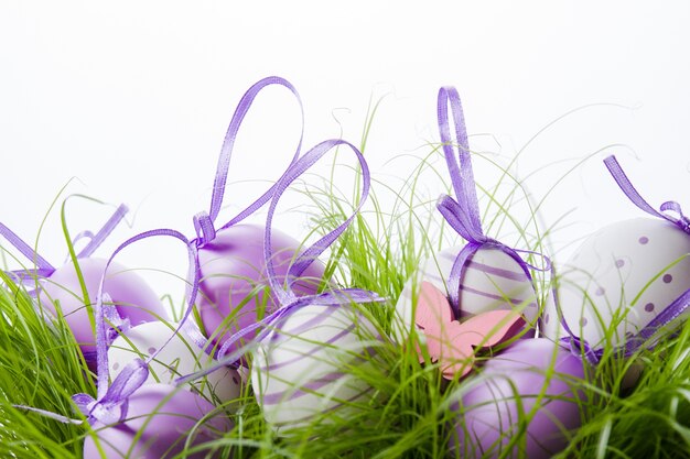 Decorative easter eggs with purple ribbon on the grass