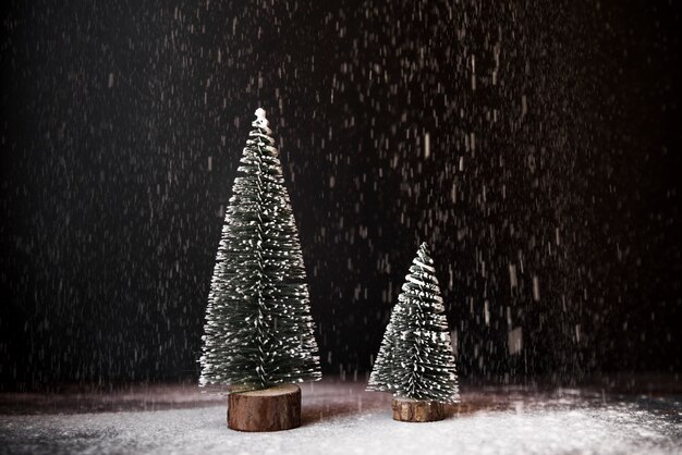 Decorative fir trees between snowfall 