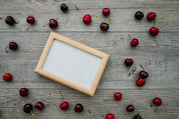 Decorative frame with cherries on wooden surface