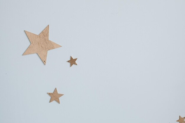 Декоративные золотые звезды на стене Крупный план декоративных золотых бумажных звезд разного размера на простой синей стене, похожей на небо