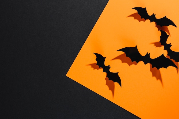 Decorative Halloween bats sitting on orange sheet of paper