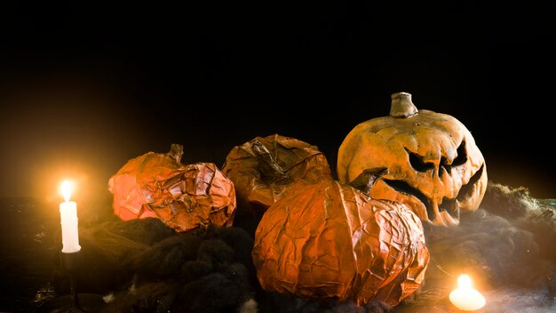 Decorative Halloween pumpkins lying among burning candles