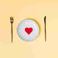 Foto gratuita cuore decorativo sul bellissimo piatto tra posate