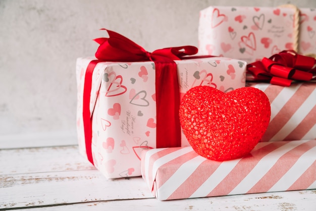 Decorative heart near heap of gift boxes in wrap