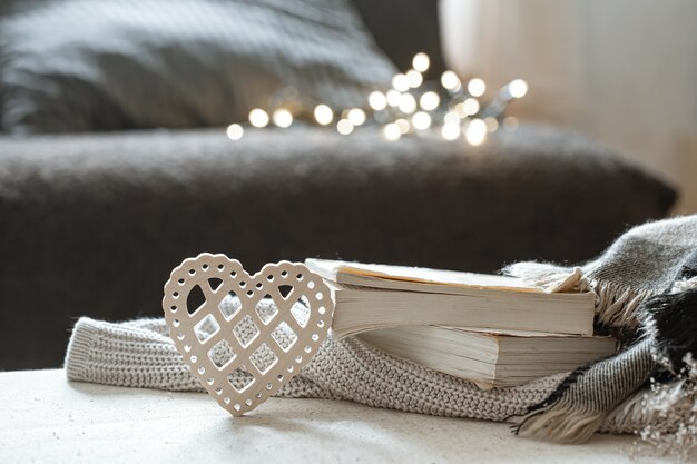 Decorative heart and a stack of books with bokeh. The concept of Valentine's day and home comfort.