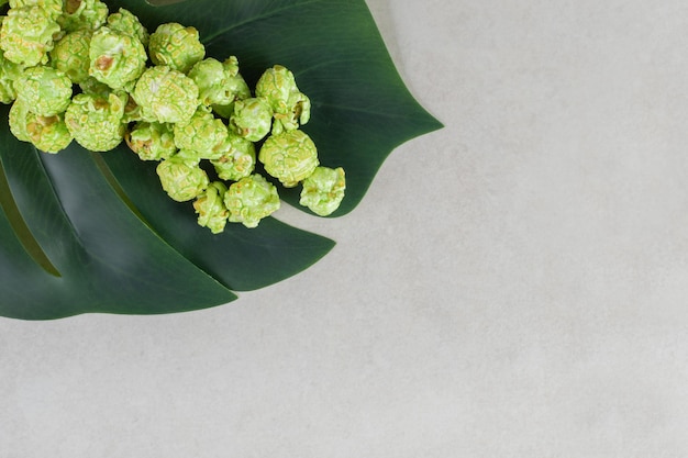 Decorative leaf underneath a small portion of candied popcorn on marble table.