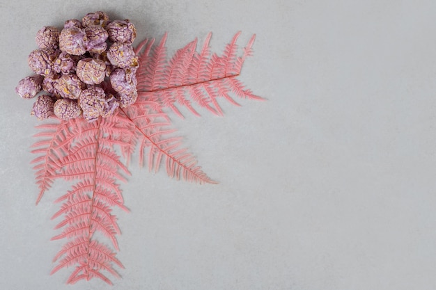 Foto gratuita foglie decorative che adornano un piccolo mucchio di caramelle popcorn sul tavolo di marmo.
