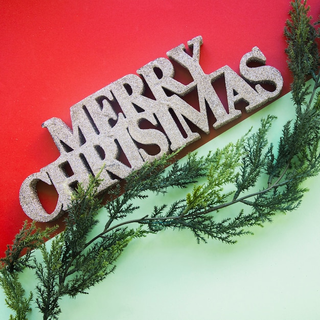 Free photo decorative merry christmas title near arborvitae twig