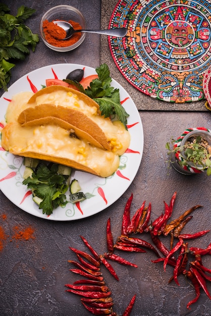 Декоративный мексиканский символ на борту возле сушеного перца чили и лаваша с начинкой на тарелке