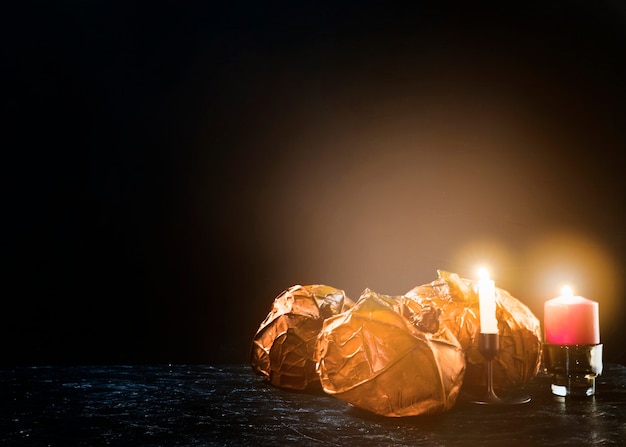 Decorative orange pumpkins lying on side near burning candles