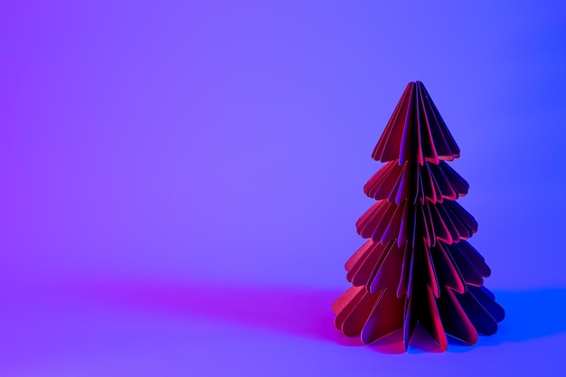 Foto gratuita albero di natale di carta decorativa su sfondo blu con luce al neon alla moda