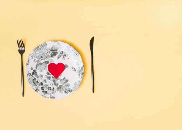 Decorative paper heart on beautiful plate between cutlery