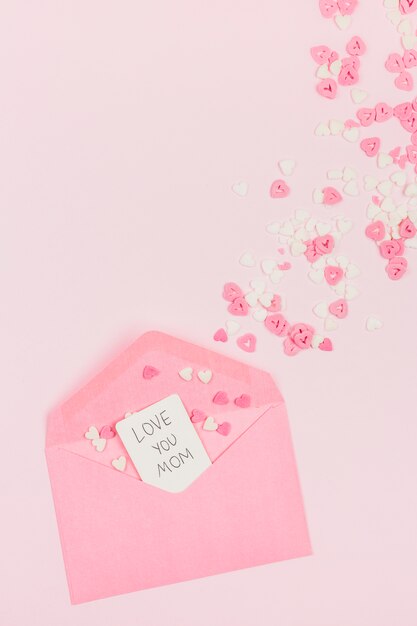 Decorative paper hearts near envelope with tag with words