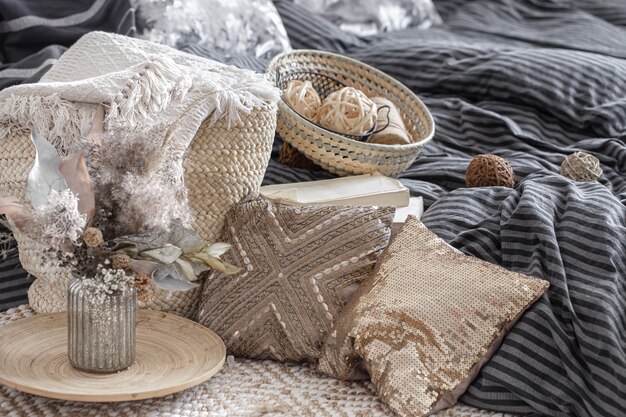 Decorative pillows, a vase with dried flowers and other elements of home decor in pastel colors close up.