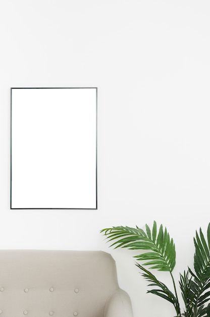 Free photo decorative plant with empty frame and sofa