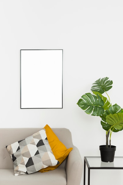 Free photo decorative plant with empty frame and sofa