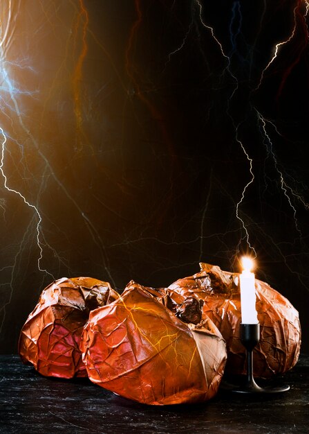 Decorative pumpkins and burning candle standing and lightning