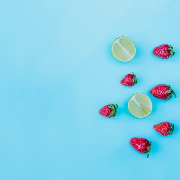 Decorative strawberries and limes on blue surface