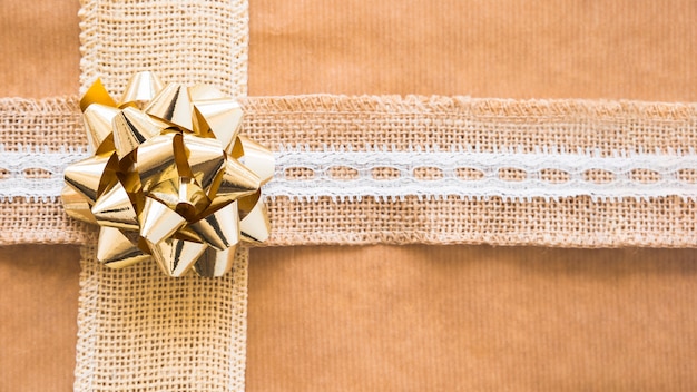 Decorative weaving ribbon and golden bow on gift paper