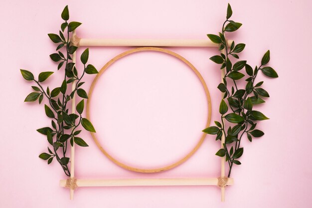 Decorative wooden empty frame with leaves on pink wall